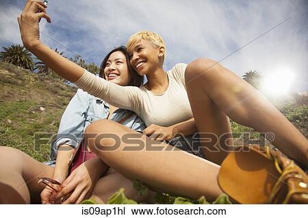 "Two female friends, outdoors, taking self portrait using smartphone" View Large Photo Image Stock Image - "Two female friends, outdoors, taking self portrait using smartphone". Fotosearch