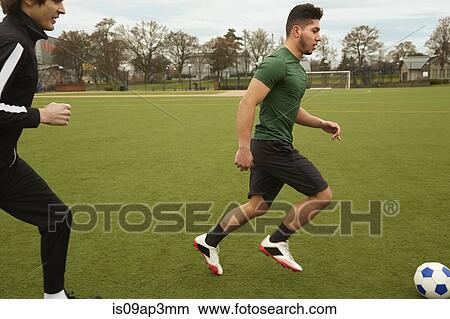 Two male soccer players running with ball on soccer pitch View Large Photo Image Picture - Two male soccer players running with ball on soccer pitch. Fotosearch