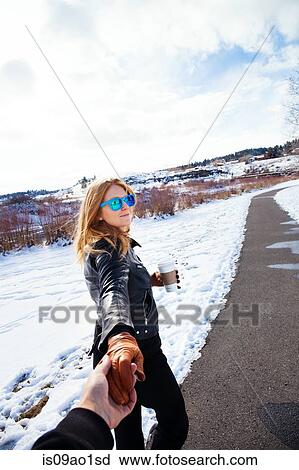 Woman holding boyfriends hand strolling in snow covered landscape View Large Photo Image Stock Image - Woman holding boyfriends hand strolling in snow covered landscape. Fotosearch