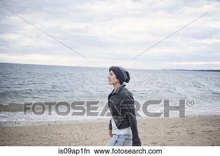 Picture - "Woman strolling on beach, Long Island, Brooklyn, New York, USA". Fotosearch