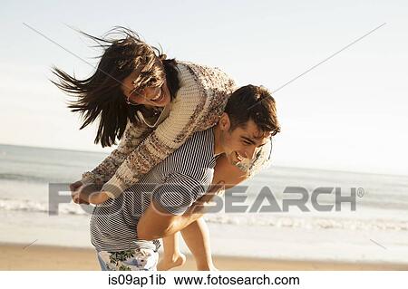 Young couple fooling around on beach View Large Photo Image Stock Image - Young couple fooling around on beach. Fotosearch