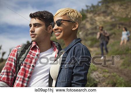 Stock Image - "Young couple, outdoors, looking at view, friends trailing behind". Fotosearch