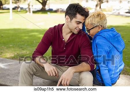 Stock Photography - "Young couple sitting on bench together, flirting". Fotosearch