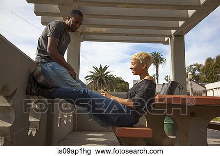 "Young couple sitting opposite each other, flirting, outdoors" View Large Photo Image Stock Image - "Young couple sitting opposite each other, flirting, outdoors". Fotosearch