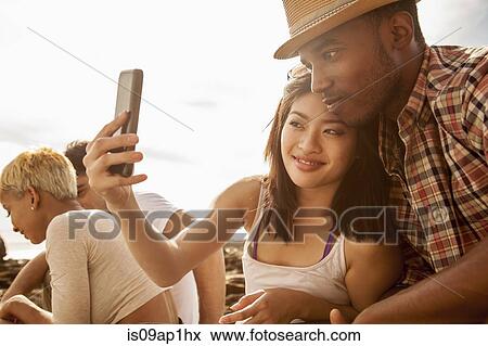 "Young couple taking self portrait on beach, using smartphone" View Large Photo Image Stock Photo - "Young couple taking self portrait on beach, using smartphone". Fotosearch