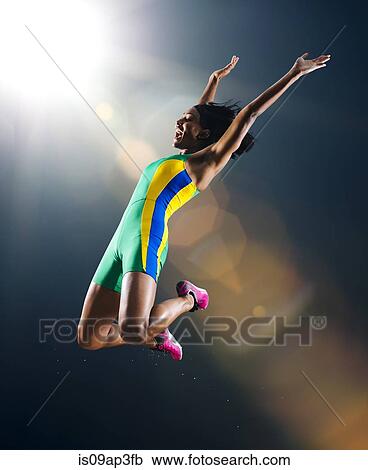 Young female athlete jumping mid air in celebration in stadium View Large Photo Image Stock Image - Young female athlete jumping mid air in celebration in stadium. Fotosearch