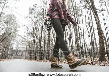 Stock Photo - Young female photographer strolling on rural forest road. Fotosearch