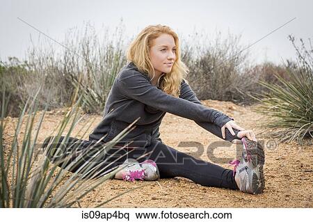 Stock Photography - Young female runner stretching to touch toes. Fotosearch