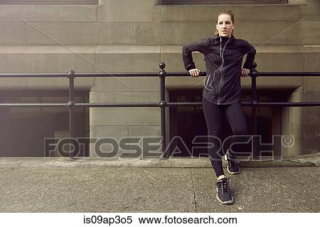 Stock Photography - Young female runner taking a break on sidewalk. Fotosearch