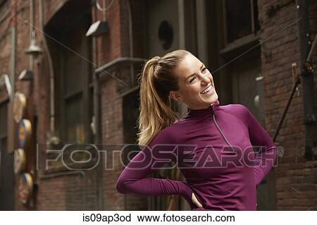 Young female runner warming up with hands on hips in alleyway View Large Photo Image Stock Image - Young female runner warming up with hands on hips in alleyway. Fotosearch