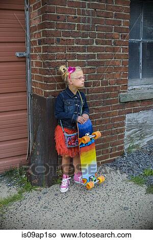 Picture - "Young girl wearing tutu and denim jacket, holding skateboard". Fotosearch