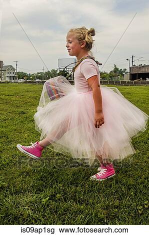 "Young girl wearing tutu and pink baseball boots, walking on grass" View Large Photo Image Stock Image - "Young girl wearing tutu and pink baseball boots, walking on grass". Fotosearch