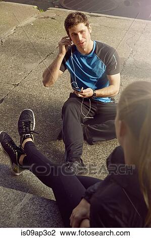 Young male and female runners chatting and listening to earphones View Large Photo Image Stock Image - Young male and female runners chatting and listening to earphones. Fotosearch