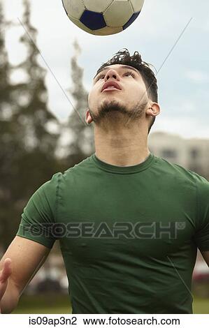 Stock Image - Young male soccer player heading ball. Fotosearch