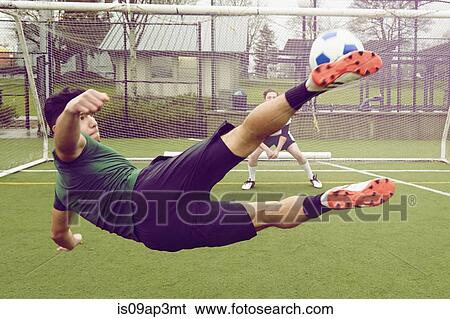 Stock Photograph - Young male soccer player kicking ball toward goal. Fotosearch