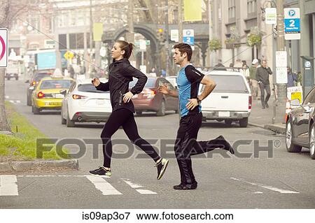 Young man and woman running across city road View Large Photo Image Stock Photo - Young man and woman running across city road. Fotosearch