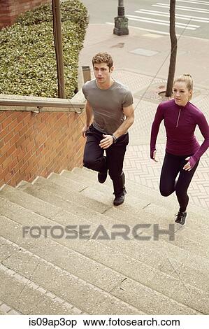 Stock Photography - Young man and woman running up city stairway. Fotosearch