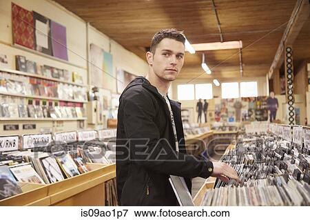 Young man browsing vinyl records in music store View Large Photo Image Stock Photo - Young man browsing vinyl records in music store. Fotosearch