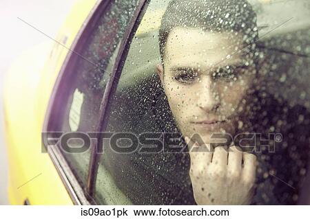 Young man gazing out of yellow cab window in rain View Large Photo Image Stock Image - Young man gazing out of yellow cab window in rain. Fotosearch