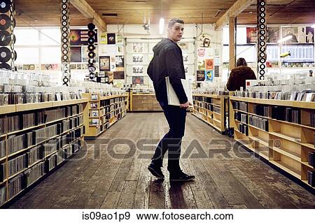 Young man holding vinyl record in music store View Large Photo Image Stock Photo - Young man holding vinyl record in music store. Fotosearch