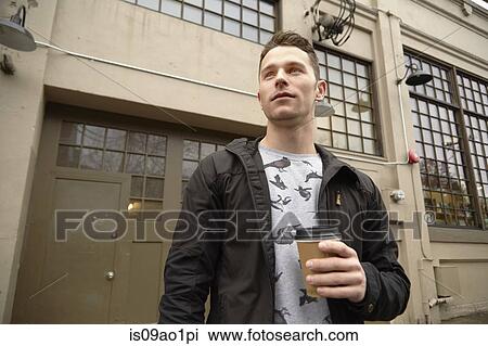 Young man in city drinking takeaway coffee View Large Photo Image Stock Image - Young man in city drinking takeaway coffee. Fotosearch