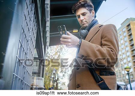 Stock Photograph - "Young man in street, using smartphone". Fotosearch
