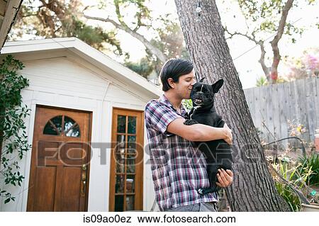 Young man kissing dog outside front door View Large Photo Image Stock Photo - Young man kissing dog outside front door. Fotosearch