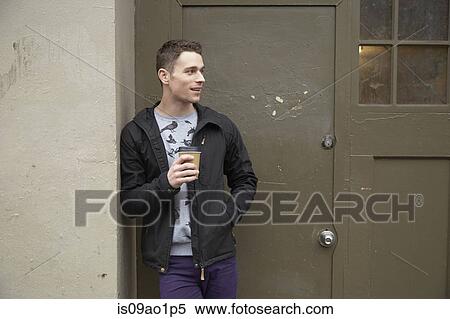 Young man leaning against doorway drinking takeaway coffee View Large Photo Image Stock Photography - Young man leaning against doorway drinking takeaway coffee. Fotosearch