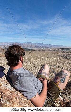 "Young man on rocks looking out at landscape, Anza-Borrego Desert State Park, California, USA" View Large Photo Image Stock Image - "Young man on rocks looking out at landscape, Anza-Borrego Desert State Park, California, USA". Fotosearch