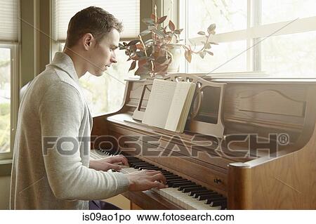 Young man playing the piano in living room View Large Photo Image Picture - Young man playing the piano in living room. Fotosearch