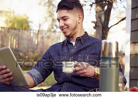 Stock Image - Young man using tablet with coffee. Fotosearch
