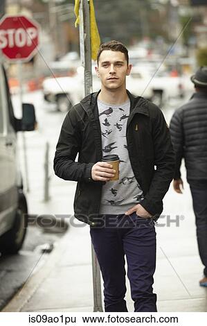 Young man walking on city sidewalk drinking takeaway coffee View Large Photo Image Stock Photograph - Young man walking on city sidewalk drinking takeaway coffee. Fotosearch