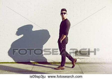 Young man walking past white wall View Large Photo Image Stock Photograph - Young man walking past white wall. Fotosearch
