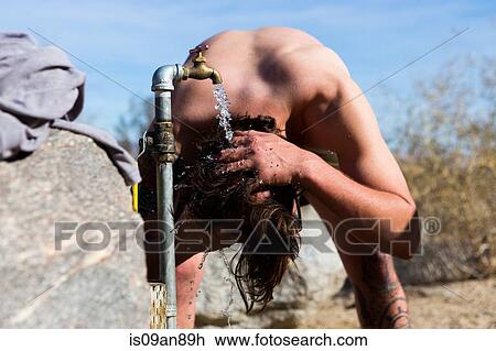 Stock Image - "Young man washing hair under campsite tap, Anza-Borrego Desert State Park, California, USA". Fotosearch
