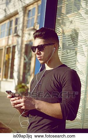 Young man wearing earphones listening to music View Large Photo Image Stock Photography - Young man wearing earphones listening to music. Fotosearch