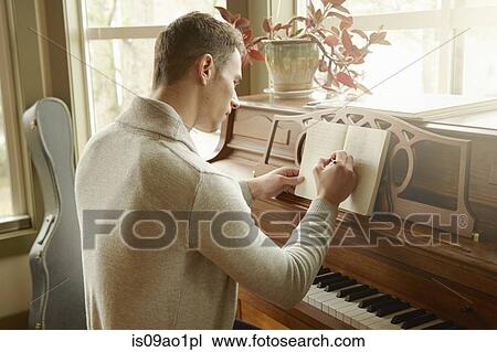 Young man writing in notebook whilst at the piano View Large Photo Image Stock Image - Young man writing in notebook whilst at the piano. Fotosearch