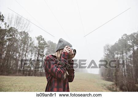 Young woman photographing in misty field View Large Photo Image Stock Image - Young woman photographing in misty field. Fotosearch