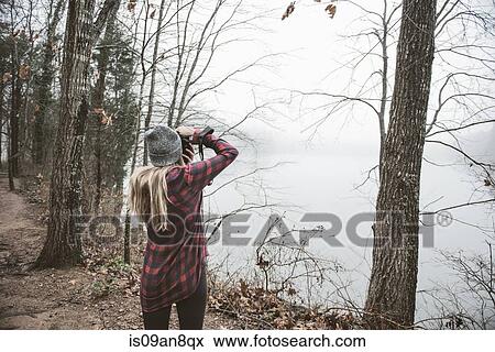Young woman photographing misty lake View Large Photo Image Stock Photo - Young woman photographing misty lake. Fotosearch