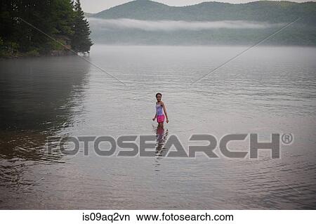 Picture - "A girl standing in water on summer vacation at Lake George, New York, USA". Fotosearch