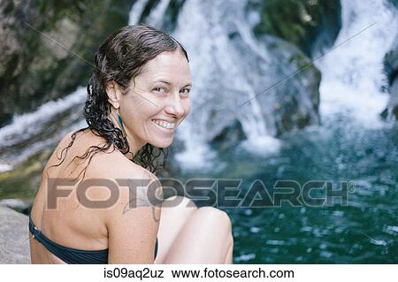 A woman sitting by a swimming hole in woods with waterfall View Large Photo Image Stock Photo - A woman sitting by a swimming hole in woods with waterfall. Fotosearch
