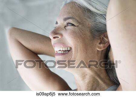 Stock Photography - Beautiful mature woman with hands behind head. Fotosearch