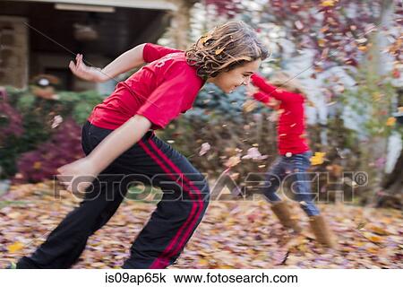 Stock Image - Brother and sister playing with autumn leaves in garden. Fotosearch