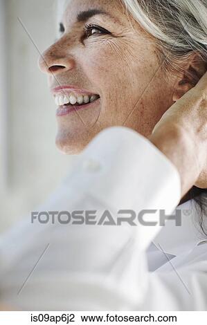 Stock Image - Close up of beautiful mature woman with hand in hair. Fotosearch