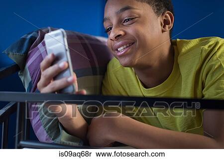Close up of teenage boy lying in bunkbed reading smartphone text View Large Photo Image Stock Photography - Close up of teenage boy lying in bunkbed reading smartphone text. Fotosearch