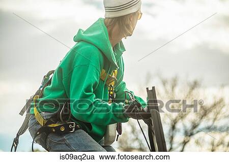 Stock Image - Construction crew member installing a solar panel on a house. Fotosearch