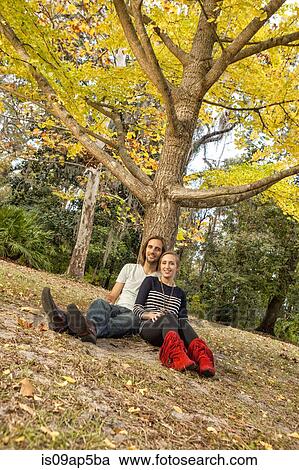 Stock Image - Couple sitting under tree. Fotosearch