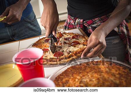 Cropped close up of womans hands cutting pizza in kitchen View Large Photo Image Picture - Cropped close up of womans hands cutting pizza in kitchen. Fotosearch