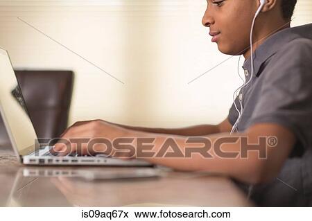 Cropped shot of teenage boy at dining table typing on laptop View Large Photo Image Stock Photo - Cropped shot of teenage boy at dining table typing on laptop. Fotosearch