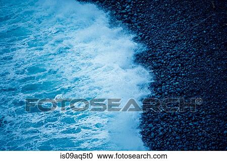 Stock Image - Detail of tidal ocean wave on shingle beach. Fotosearch