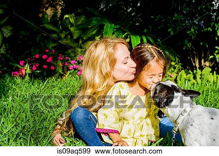 Stock Photo - Dog licking girl's face in garden. Fotosearch